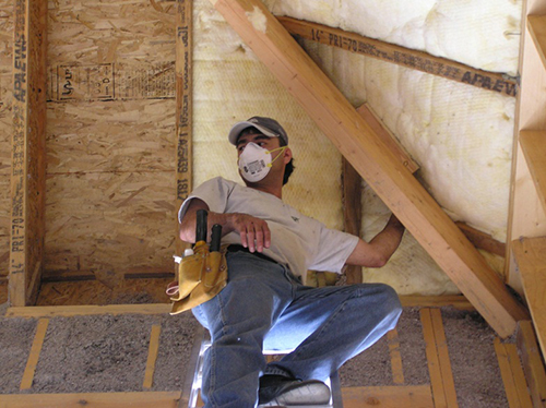 A fiberglass batt being installed in an attic